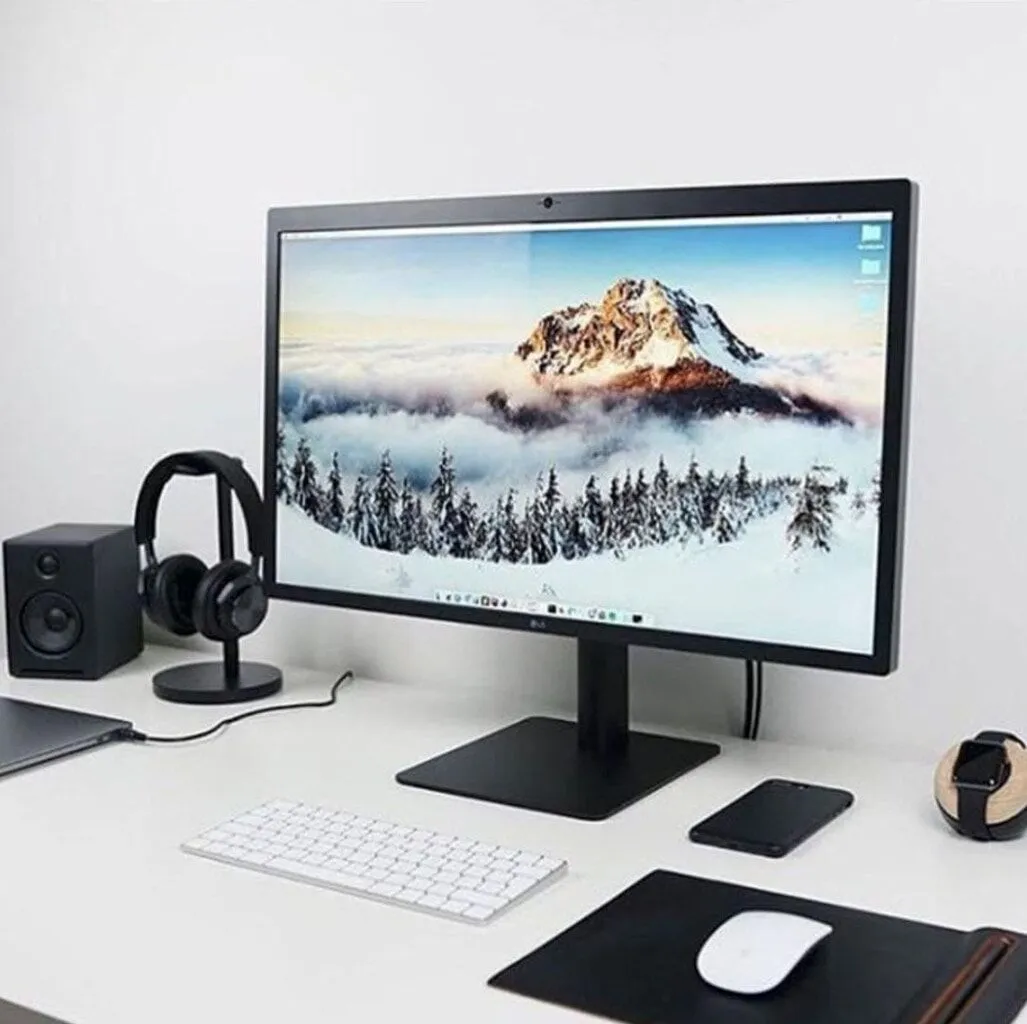 Walnut Audioengine speakers on a dark desk beside a monitor and headphones
