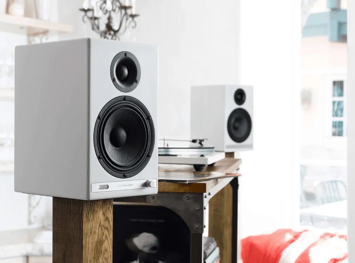 White Audioengine speakers on wooden stands in a bright living room